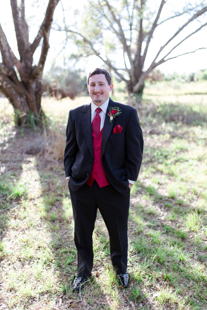 Red Rose, Boutonniere, Tuxedo, Red Vest, Hands in pockets, Groom poses, Groom, Groom photo ideas,  Wedding, Wedding Ring, Red, Married, Wedding Dress, Ft. Meyers, Florida
