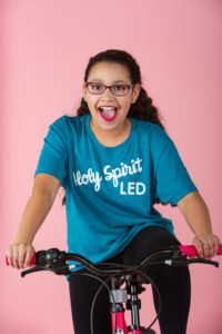 slime, purple, teal aqua, turquoise, pink, squishies, squishy's, bows, cheerleader, curly hair, orange, white bow, turquoise shirt, tween girl, 11 years old, fun, silly, holy spirit led t shirt pink backdrop, pink bicycle, glasses