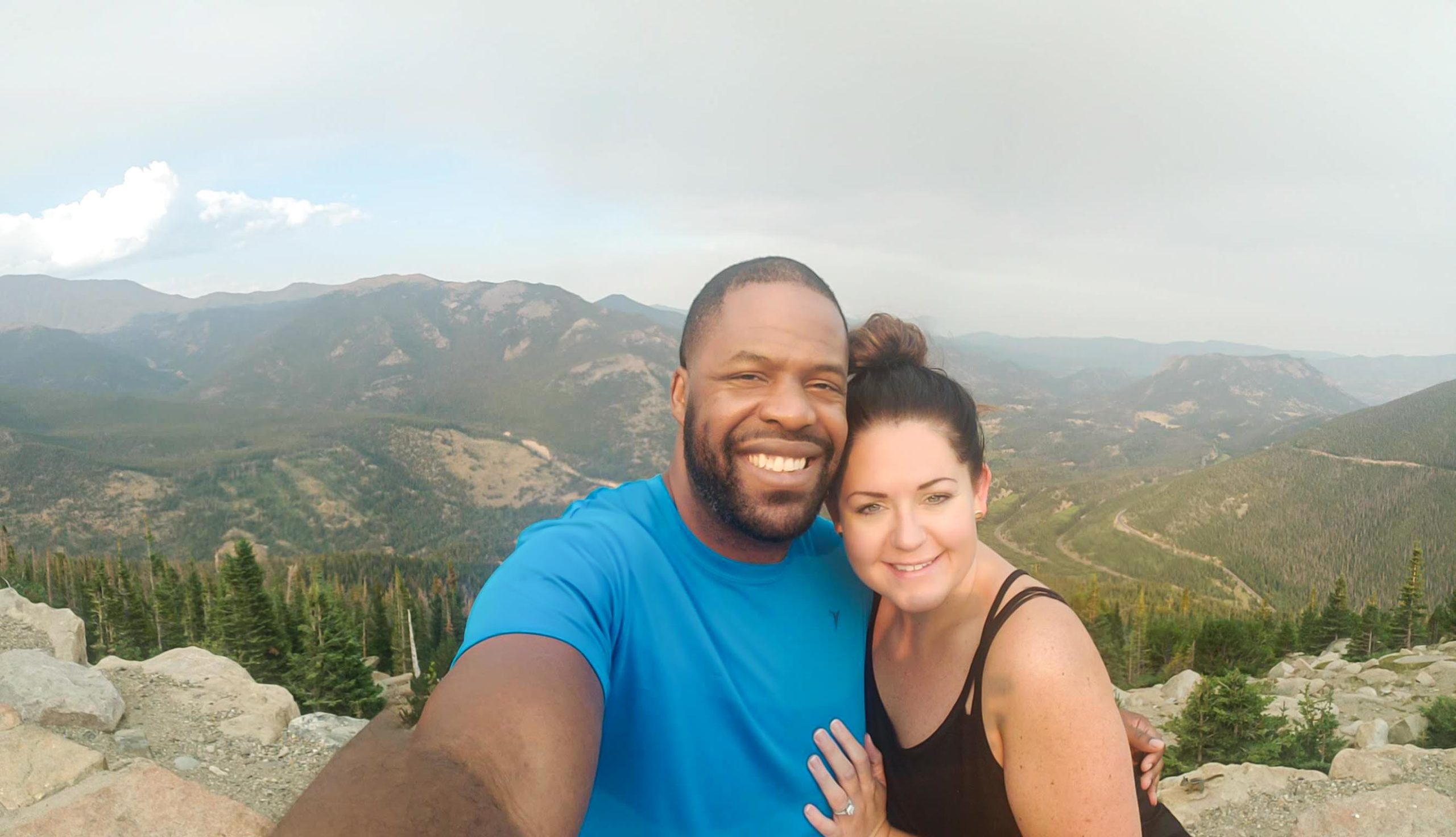 Jill Blue Photography and her husband embrace while taking a selfie on trail ridge rd with the rocky mountains behind them