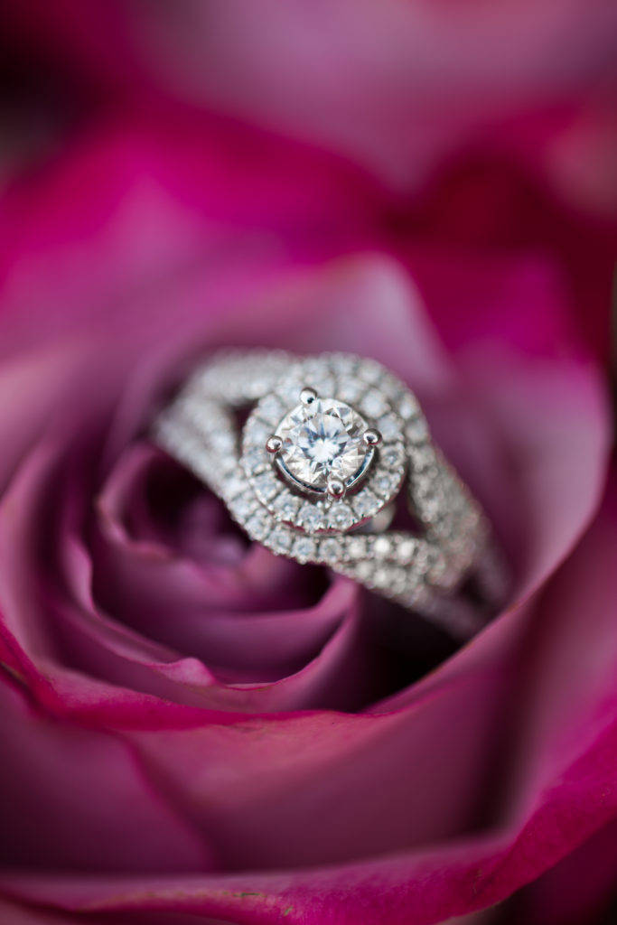 Engagement ring lays in the center of a fuchsia pink rose