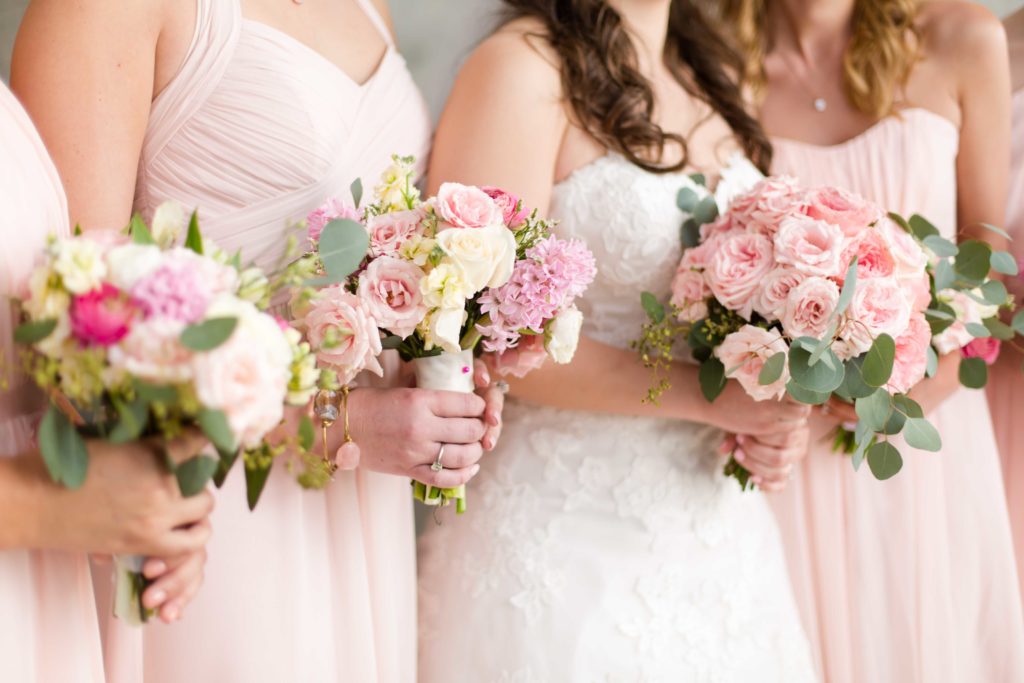 Bride and bridal party posing with pink rose bouquets on a wedding day