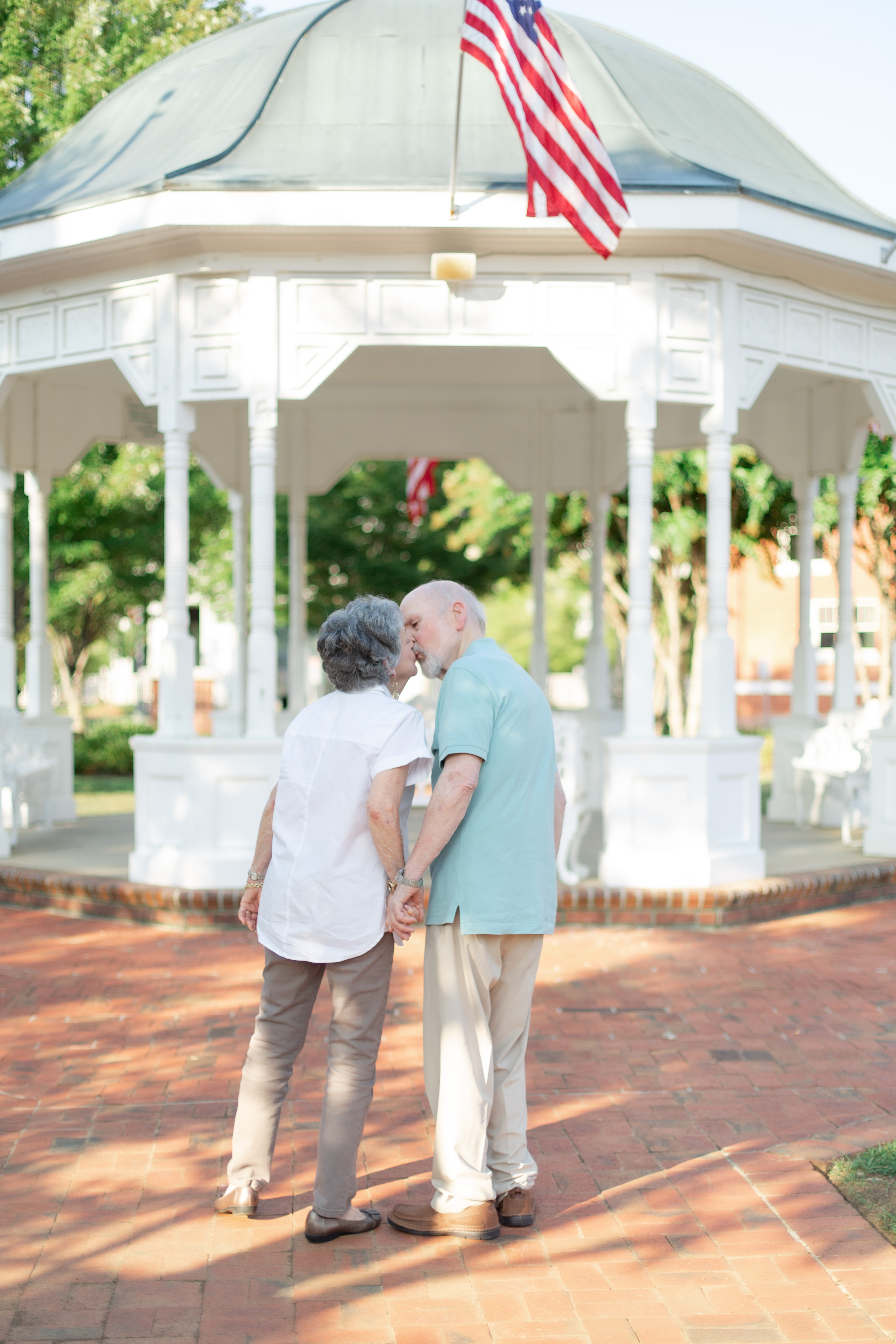 Couple leans in for a kiss in front of American flag in downtown Canton
