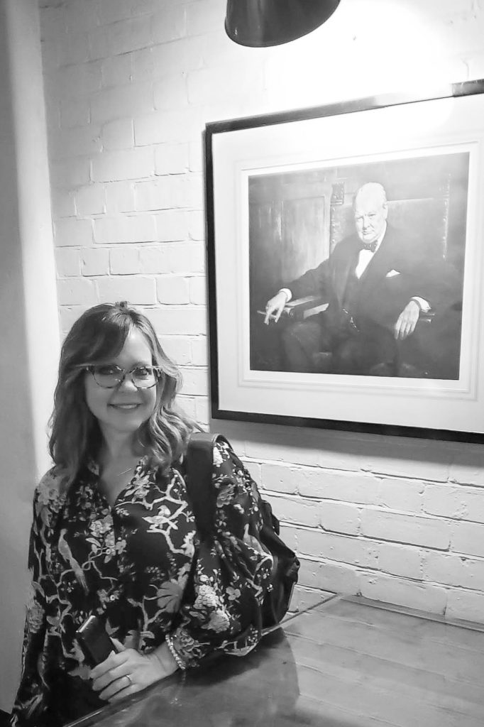 Patrice poses next to portrait of Winston Churchill in the War Rooms