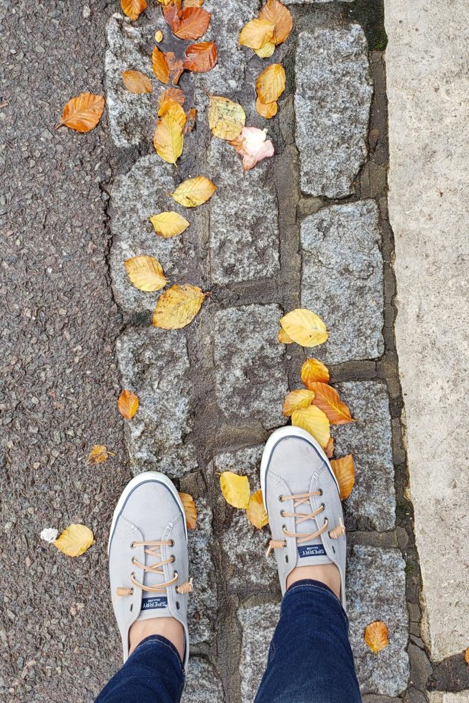 pair pf sperry sneakers on cobblestones with fallen leaves in london